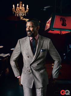 a man in a gray suit standing next to a chandelier with red lights