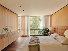 a large bed sitting in a bedroom next to a tall wooden cabinet and window sill