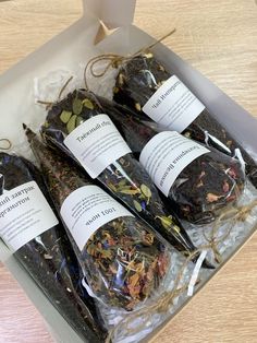 four different types of teas in a box on a wooden table with tags attached to them