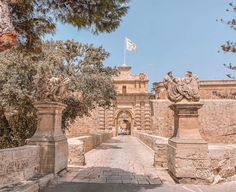 an old stone bridge with statues on each side and a flag flying in the background