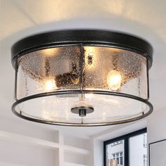 a light fixture in a room with white walls and windows on the wall behind it