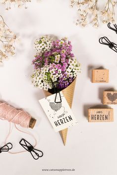 some flowers are sitting in a cone on a white surface next to several rubber stamps