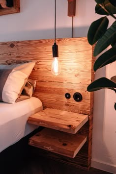 a bed with a wooden headboard and night stand next to a potted plant