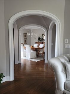 an archway leads to the dining room and living room in this modern home, with hardwood flooring