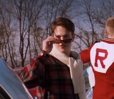 a man in plaid shirt talking on cell phone next to woman with red and white sweater