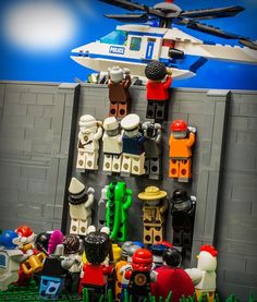 legos are arranged in front of a wall with a helicopter on it and people standing around