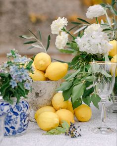 lemons and white flowers are arranged on a table with blue and white vases