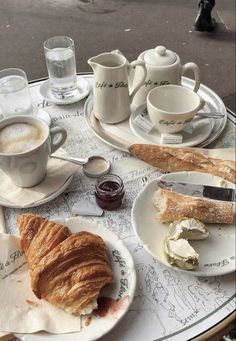 a table topped with plates and cups filled with breakfast foods on top of each other