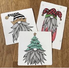 three cards with christmas designs on them sitting on a wooden table next to each other