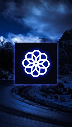 an illuminated sign on the side of a road at night with clouds in the background