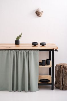 a wooden table topped with black plates next to a vase and potted plant on top of it