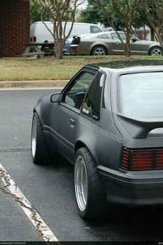 a car parked in a parking lot with its door open and the back window missing