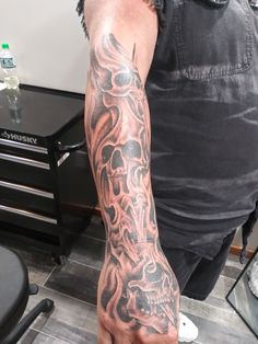 a man with a tattoo on his arm is standing in front of a table and chair