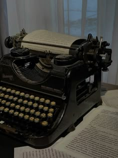 an old fashioned typewriter sitting on top of a table next to some books and papers