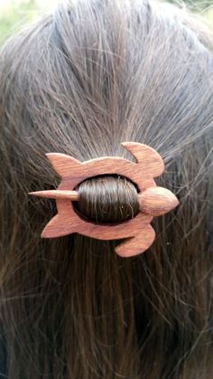 the back of a woman's head with a wooden hair clip