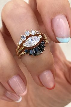 a woman's hand with two rings on her fingers and one ring has an oval shaped