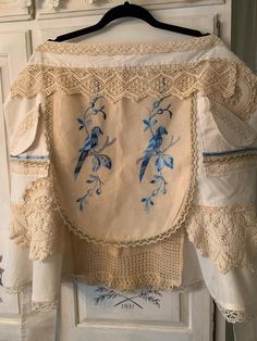 an old blouse with blue birds on it hanging from a hanger in front of a white cabinet