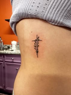 a woman's stomach with a cross tattoo on it