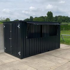 a black portable toilet sitting on top of a cement floor next to a green field