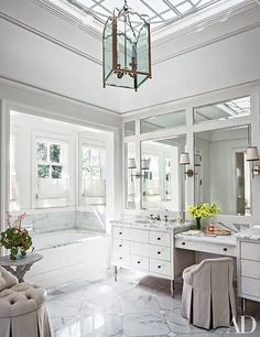 a white bathroom with marble floors and large mirrors on the wall above the bathtub