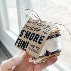 a person holding up a bag with some cookies in it that says having you here made us s'more fun