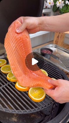 someone is cooking salmon on the grill with lemons