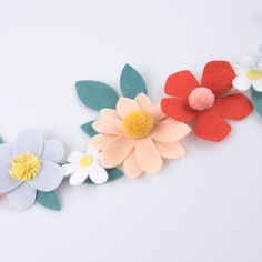 several felt flowers are arranged on a white surface