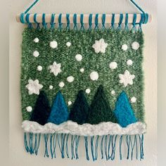 a green wall hanging with trees and snowflakes