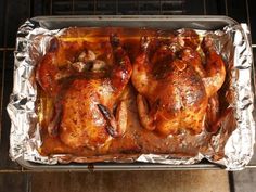 two whole chickens sitting on top of tin foil in an oven, ready to be cooked