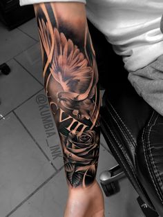 a man's arm with an eagle and roses tattoo on it