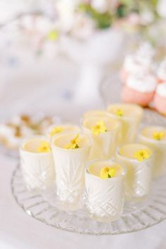 Vanilla flavoured panna cotta in small glass containers and a crystal serving platter decorated with a yellow edible spring flower - created by MonAnnie Cakes as part of the Patisseria luxury patisserie table, photo by Cristina Ilao Yellow Dessert Table, Frilly Cake, Wedding Cake And Dessert Table, Cake And Dessert Table, Table With Flowers, Small Glass Containers, Hedsor House, Mint Cheesecake, Cakes Floral