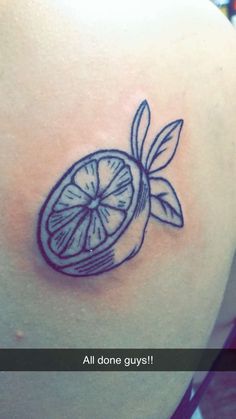 a tattoo on the back of a woman's shoulder that has a slice of lemon in it