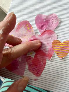 someone is making heart shaped paper flowers on a piece of paper that they are holding