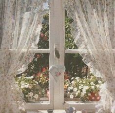 there is a window with white curtains and flowers on the windowsill in front of it