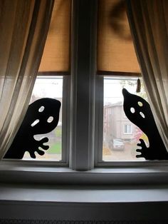 the silhouettes of two animals are seen through an open window with drapes in front of them