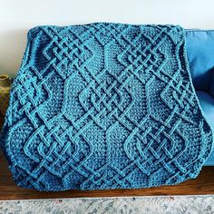 a blue crocheted blanket sitting on top of a couch