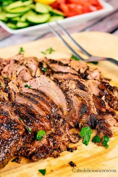 the meat is sliced and ready to be served on the cutting board with salad in the background