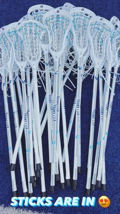 there are many lacrosse sticks lined up in the same row and one is white with blue lettering that says sticks are in