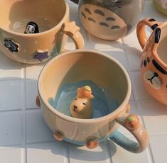 three ceramic mugs with animals in them sitting on a counter top next to each other