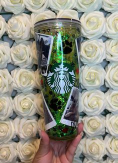 the starbucks cup has been decorated with pictures and glitters, while it is surrounded by white roses