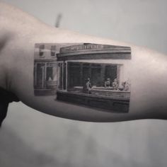 a black and white photo of a storefront with people on the window sill