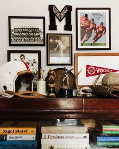 there are many framed sports memorabilia on the shelf in front of the bookshelf