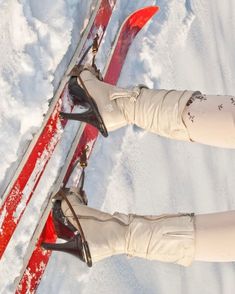 the legs and feet of a woman on skis in the snow with red poles