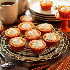 cupcakes with white frosting sitting on a wire rack next to plates and utensils