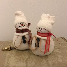 two snowmen with hats and scarfs on top of a table next to a gold object