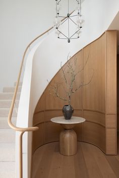 a vase sitting on top of a wooden table next to a stair case in a house