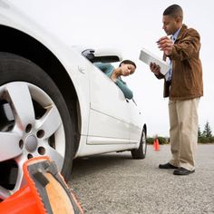 a man standing next to a white car with a woman in the back seat looking at something