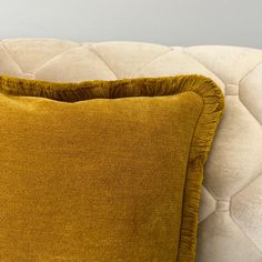 a yellow pillow sitting on top of a white couch