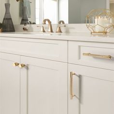 a bathroom with white cabinets and gold hardware on the handles, along with a candle holder