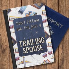 two passport covers sitting next to each other on top of a wooden table with the words don't follow me i'm just a training spouse